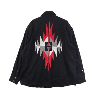 May include: Black long-sleeved shirt with a geometric pattern on the back. The design incorporates red, white, and grey shapes. The shirt has a button-down front and cuffs.