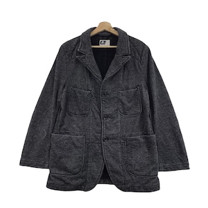 Puede incluir: Un blazer gris oscuro con una apariencia texturizada, con solapas con muescas, tres botones y dos bolsillos delanteros grandes. La chaqueta está colgada en una percha de madera. El blazer tiene un diseño clásico.