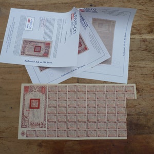 Puede incluir: Un billete de banco chino vintage con un sello rojo y un patrón repetido de sellos rojos más pequeños. El billete de banco está impreso en papel crema y tiene el número "1000" impreso en la esquina inferior izquierda. El billete de banco está en buen estado y ha sido autenticado por PASS-CO.
