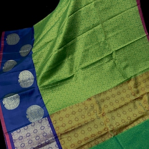 May include: A vibrant textile featuring a combination of colors and patterns. The fabric showcases a large section of bright green with a repeating pattern, a gold band, and a deep blue border with decorative silver accents. The edges are trimmed with a pink border and blue tassels.