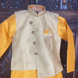 May include: A gold and yellow kurta set with a patterned vest and a solid yellow bottom. The vest has a pocket on the left side with a decorative pin.