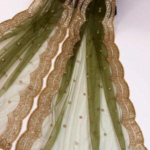 May include: Olive green sheer fabric with gold-colored embroidery and embellishments. The fabric features a scalloped edge design with intricate detailing. Small gold sequins are scattered across the surface, adding a touch of sparkle.