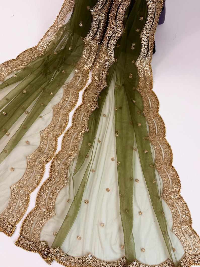 May include: Olive green sheer fabric with gold-colored embroidery and embellishments. The fabric features a scalloped edge design with intricate detailing. Small gold sequins are scattered across the surface, adding a touch of sparkle.