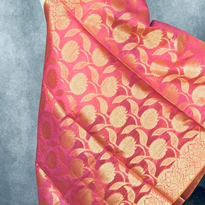 May include: A pink and gold fabric with a floral pattern. The fabric has a subtle sheen and is lightweight.