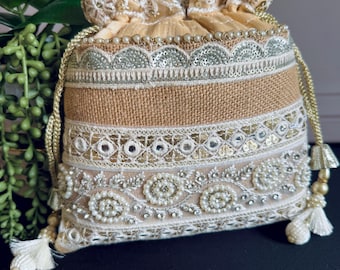 May include: A beige drawstring bag with intricate embroidery and sequins. The bag has a brown jute base and is decorated with white beads and gold accents.