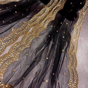 May include: Black sheer fabric with gold embroidery and scalloped edges. The fabric is delicate and has a luxurious feel.