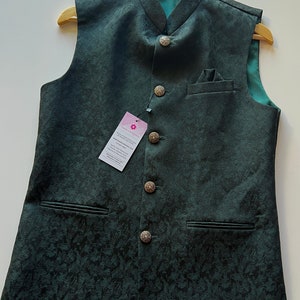 Puede incluir: Un chaleco de color verde oscuro con estampado, cuello mandar&iacute;n y botones plateados. El chaleco tiene dos bolsillos en la parte delantera y un bolsillo en el lado izquierdo del pecho.