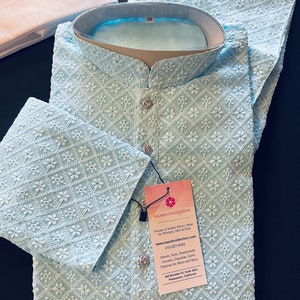 Pu&ograve; includere: Una kurta ricamata di colore azzurro chiaro con un motivo floreale bianco. La kurta ha un colletto alla coreana e una chiusura con bottone. L'etichetta sulla kurta recita "KAASH COLLECTION House of Indian Ethnic Wear for Women, Men & Kids www.kaashcollection.com 415-827-0482 Sarees, Suits, Readymade blouses, Dupattas, Kurta Pajamas for Mens and Boys 428 Boulder Ct, Suite 206-L Pleasanton, California"