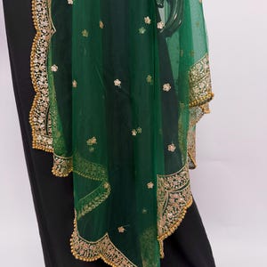 Peut inclure: &Eacute;charpe vert &eacute;meraude transparente avec broderies dor&eacute;es et motifs floraux. Les bords sont orn&eacute;s d'une bordure dor&eacute;e festonn&eacute;e. Le tissu est orn&eacute; de petits accents dor&eacute;s. Accessoire d&eacute;coratif.