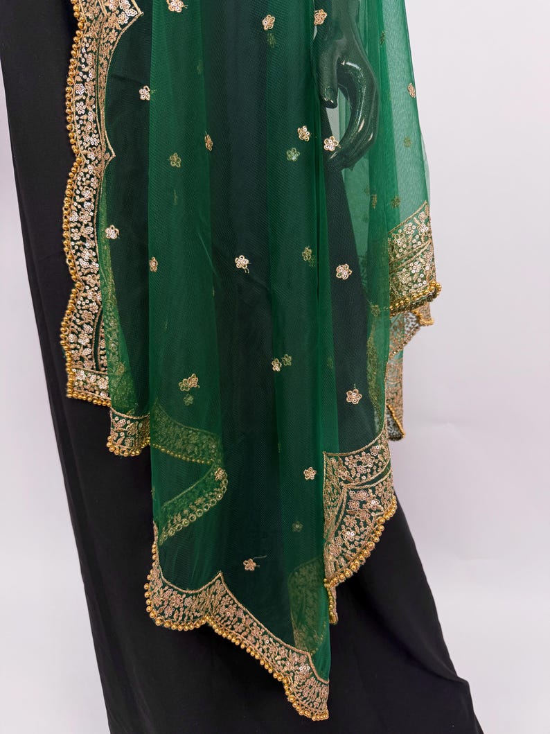 Peut inclure: &Eacute;charpe vert &eacute;meraude transparente avec broderies dor&eacute;es et motifs floraux. Les bords sont orn&eacute;s d'une bordure dor&eacute;e festonn&eacute;e. Le tissu est orn&eacute; de petits accents dor&eacute;s. Accessoire d&eacute;coratif.