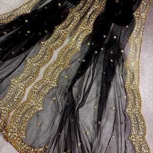 May include: Black sheer fabric with a gold embroidered border. The border features a scalloped design with small gold beads and sequins.