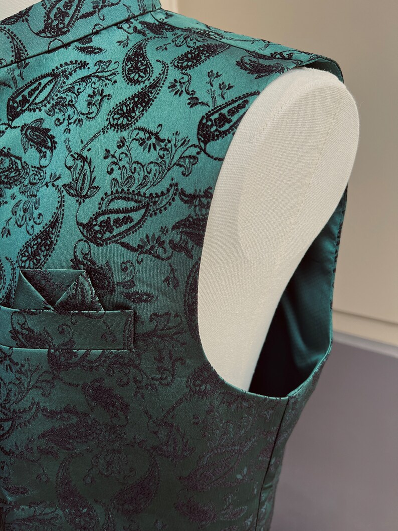 May include: A green paisley patterned vest with a black pocket square. The vest is made of a soft, luxurious fabric and has a classic, timeless design.