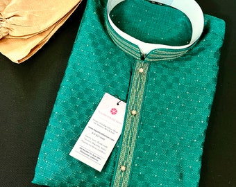 May include: A green kurta with gold trim and a white collar. The kurta is folded and has a small tag attached with the text "KAASH COLLECTION Home of Indian Ethnic Wear for Women, Men & Kids www.kaashcollection.com 415-227-2483 Sarees, Suits, Lehengas, Kurta, Dresses for Men and Boys 404 Dublin Ct Suite 200 Pleasanton, California"