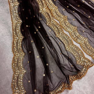 May include: Black sheer fabric with gold embroidered trim. The trim features a scalloped design with small beads.
