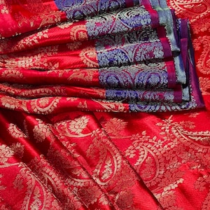 May include: Red silk saree with a paisley pattern and a blue and silver border.