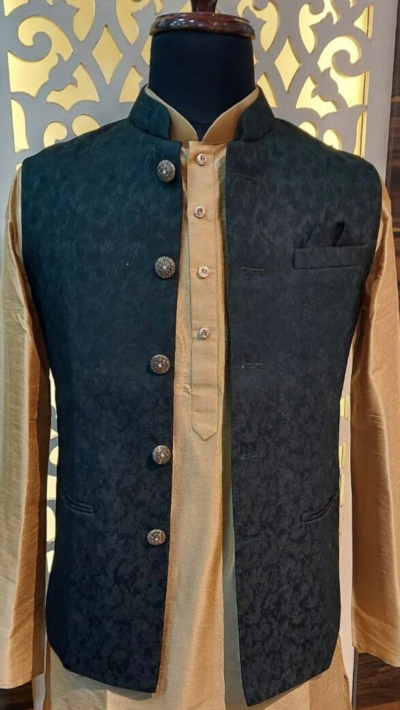 Puede incluir: Un chaleco negro estampado con cuello mandar&iacute;n y botones decorativos. El chaleco se lleva sobre una camisa dorada.