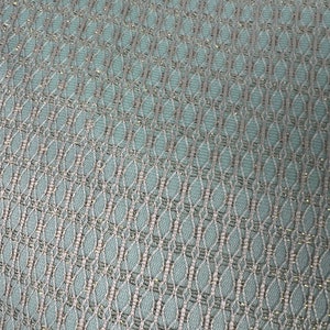 May include: A close-up of a light blue fabric with a silver metallic pattern. The fabric has a woven texture and a subtle sheen.