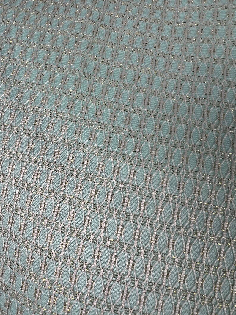May include: A close-up of a light blue fabric with a silver metallic pattern. The fabric has a woven texture and a subtle sheen.