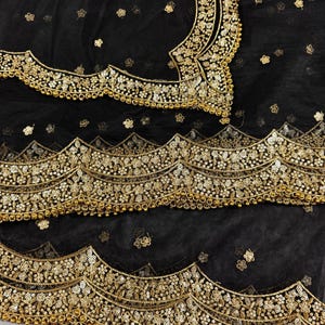 May include: Black sheer fabric with gold embroidery and beading. The fabric has a scalloped edge and is decorated with floral patterns.