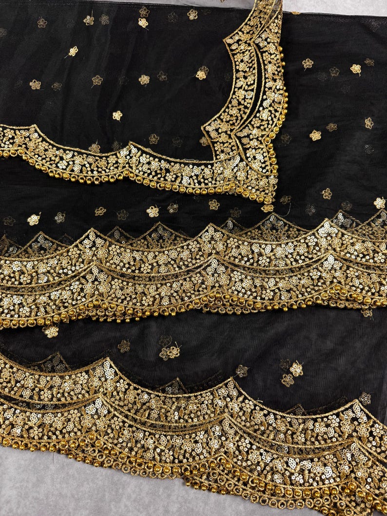 May include: Black sheer fabric with gold embroidery and beading. The fabric has a scalloped edge and is decorated with floral patterns.