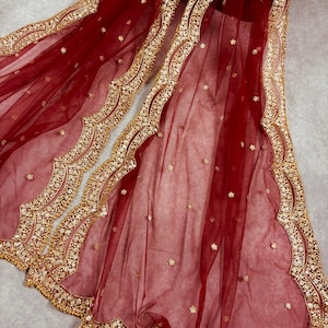 Op de afbeelding: Een maronkleurige net dupatta met een gouden geborduurde rand. De rand heeft een gegolfd ontwerp met kleine kralen en pailletten.