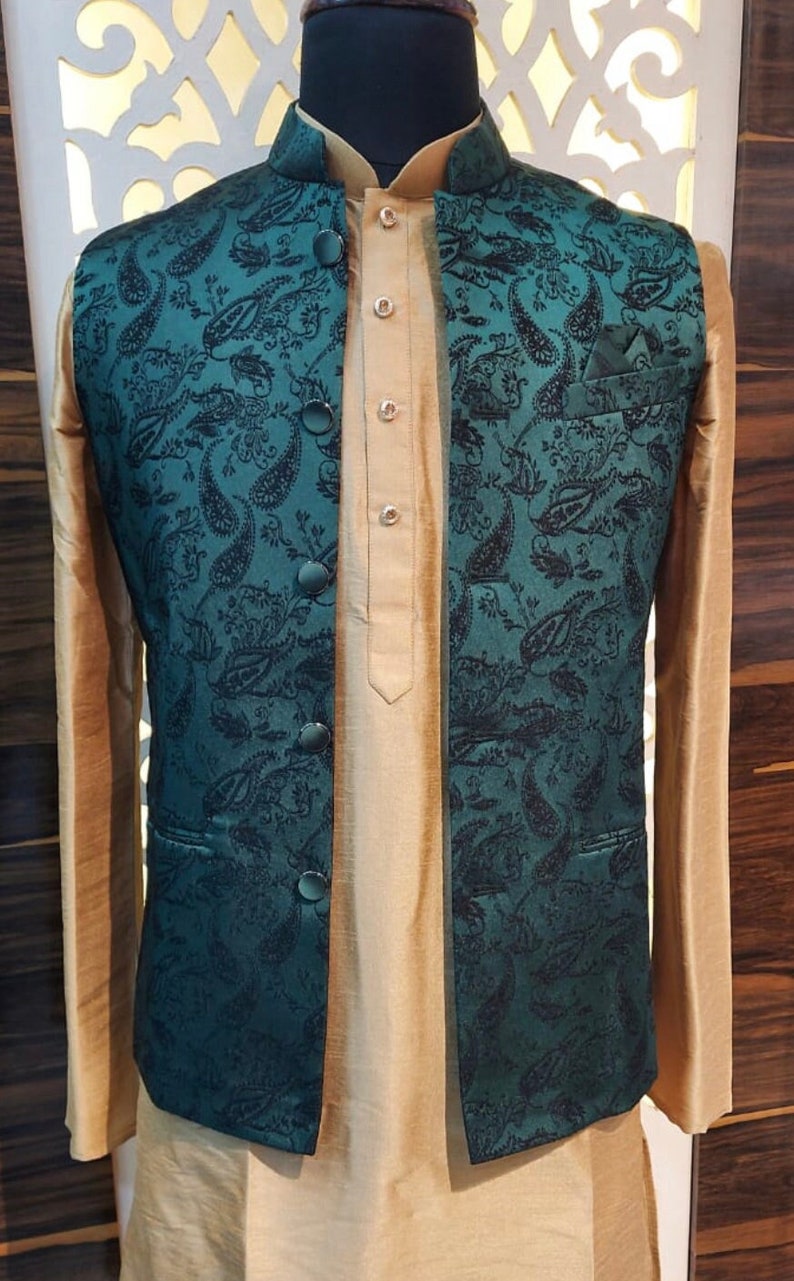 May include: A teal waistcoat with a paisley pattern and black buttons. The waistcoat is worn over a gold kurta.