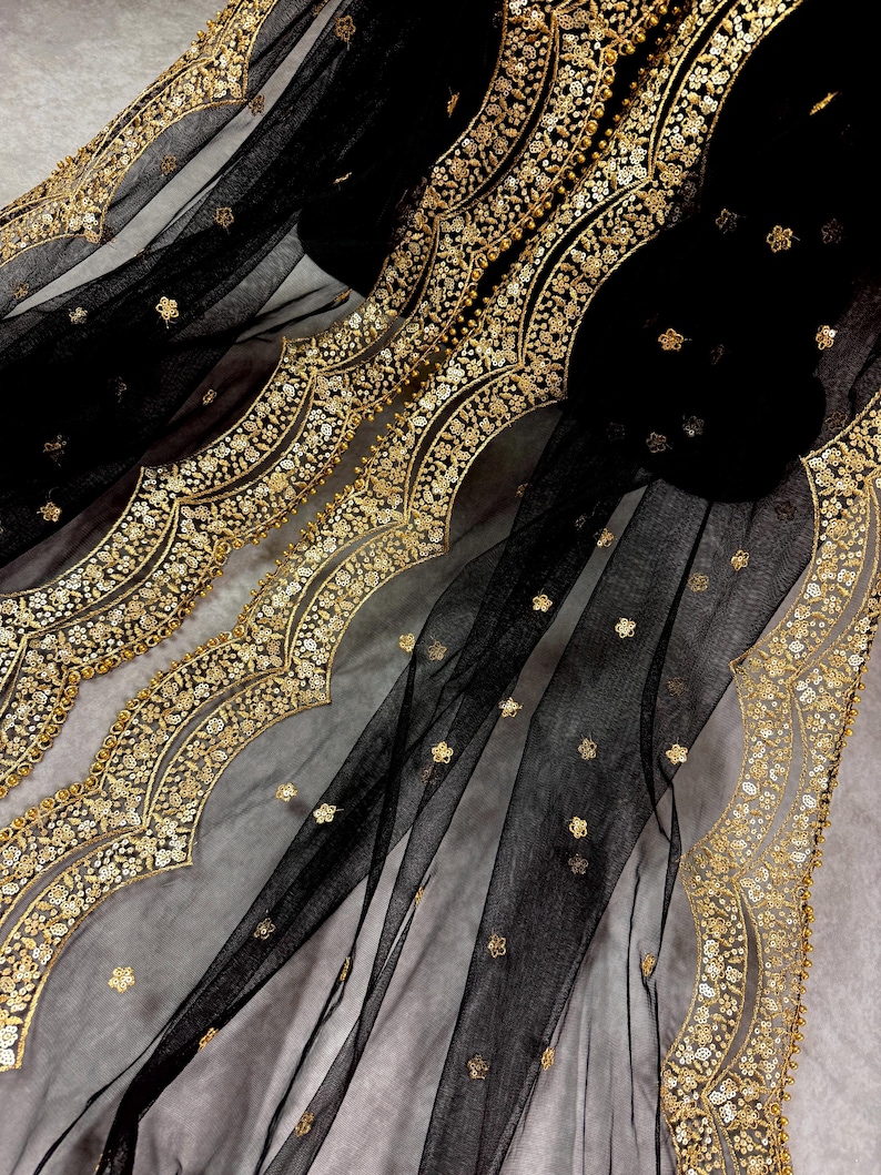 May include: Black sheer fabric with a gold embroidered border. The border features a scalloped design with floral motifs.
