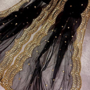 May include: Black sheer fabric with a gold embroidered scalloped border. The fabric is decorated with small gold dots.
