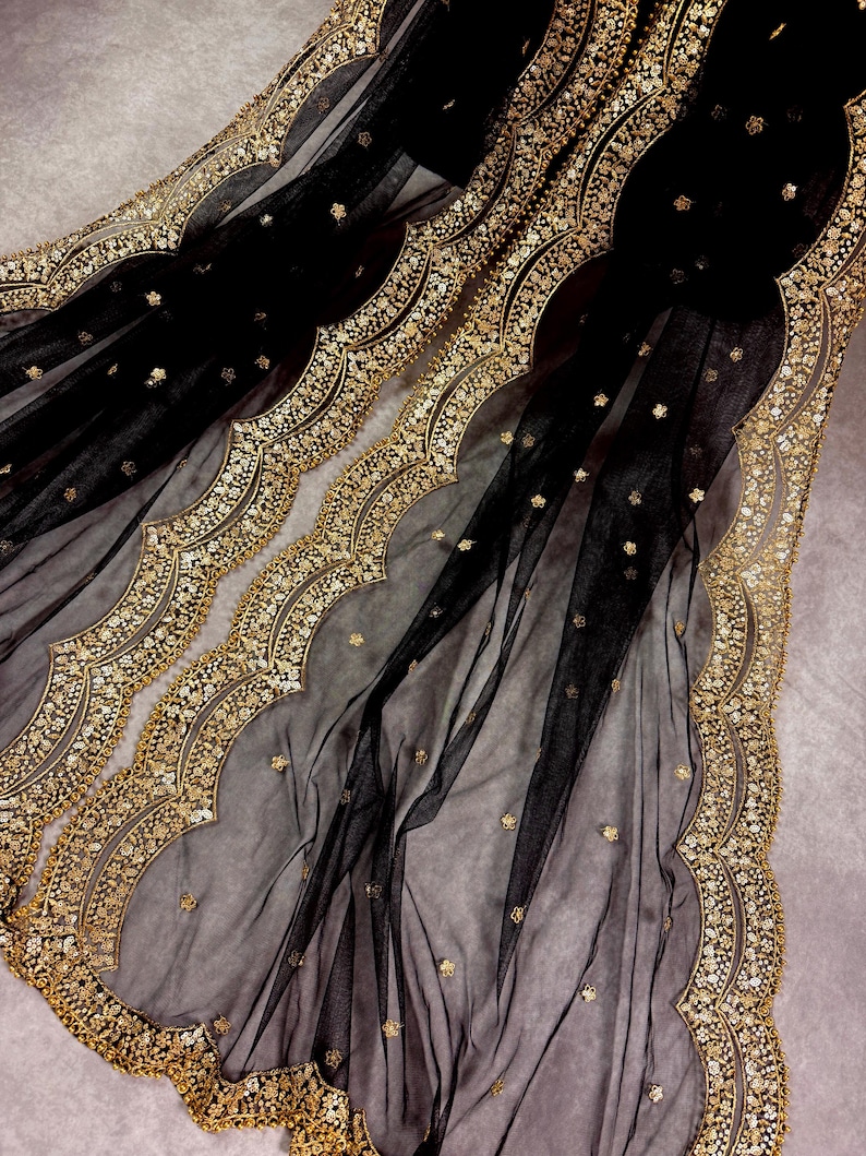 May include: Black sheer fabric with a gold embroidered scalloped border. The fabric is decorated with small gold dots.