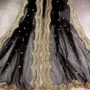 May include: Black sheer fabric with gold embroidered trim. The trim features a scalloped design with small beads and sequins.