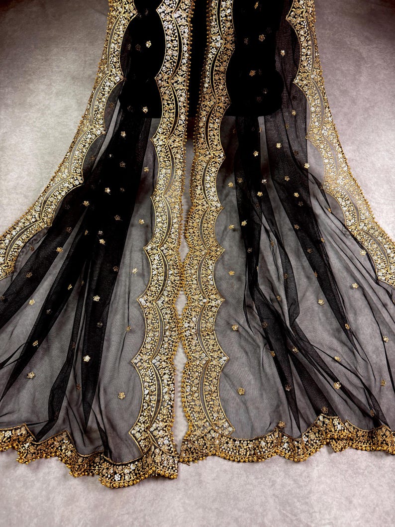 May include: Black sheer fabric with gold embroidered trim. The trim features a scalloped design with small beads and sequins.