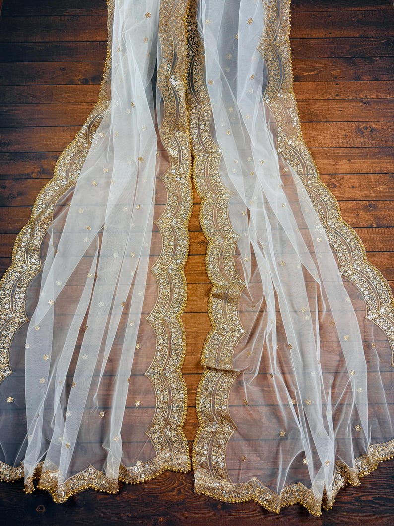 May include: White sheer fabric with a gold beaded trim. The trim features a scalloped edge and intricate details.