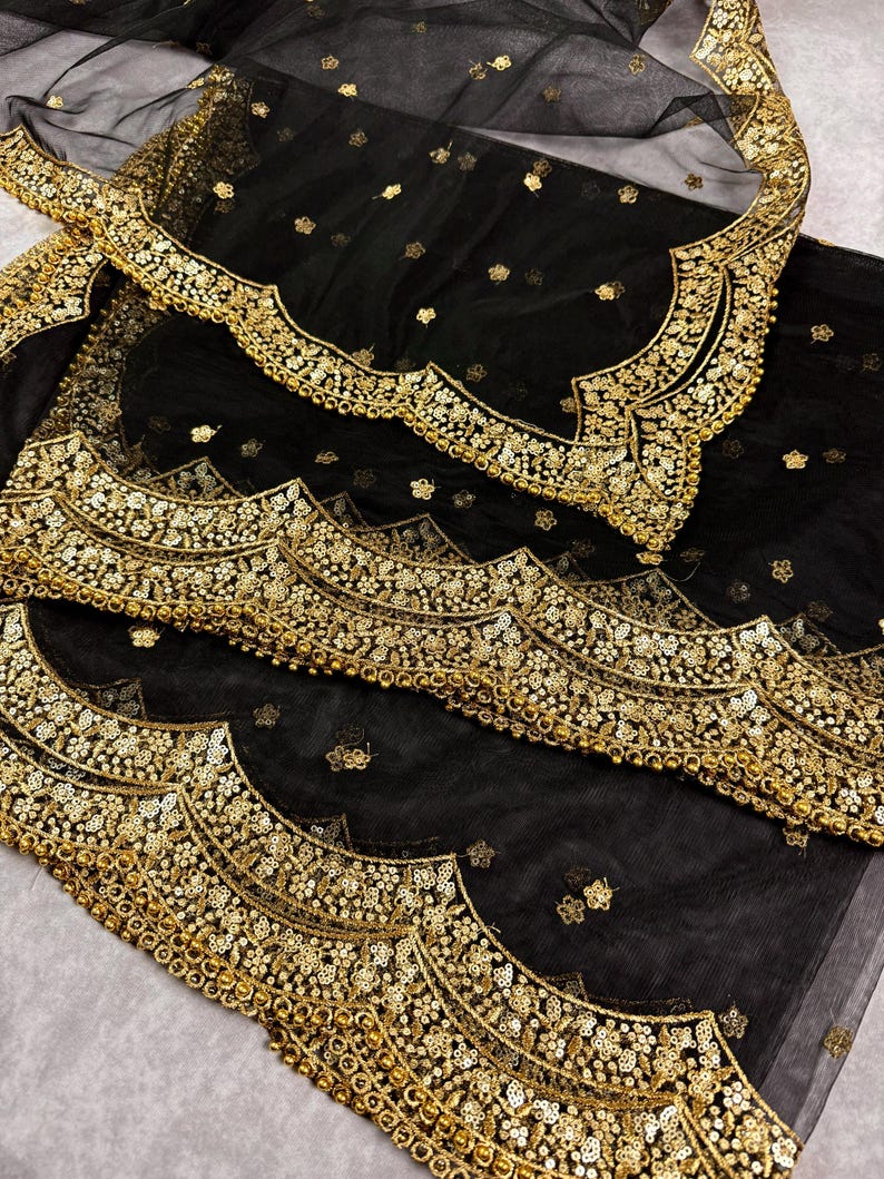 May include: Black sheer fabric with a gold embroidered border. The border features a scalloped design with sequins and beads.