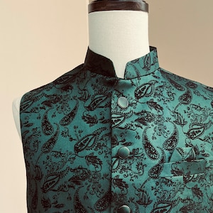 May include: A green paisley patterned vest with black buttons. The vest has a mandarin collar and a pocket on the right side.