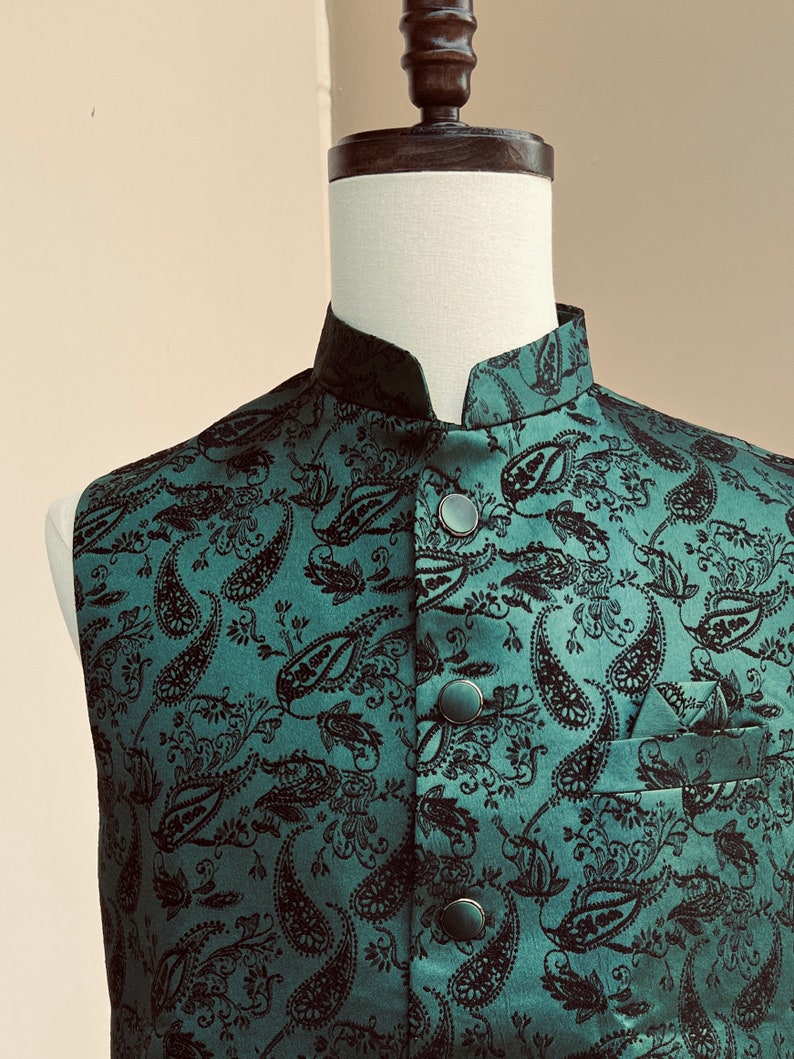 May include: A green paisley patterned vest with black buttons. The vest has a mandarin collar and a pocket on the right side.