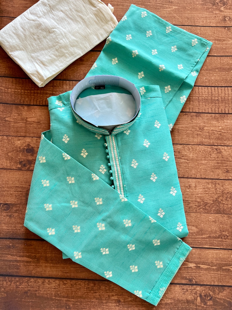 Pode incluir: Uma kurta azul turquesa com um padr&atilde;o geom&eacute;trico branco e prateado. A kurta tem um colar mandarim e um fecho de bot&atilde;o. &Eacute; feita de um tecido macio e leve.