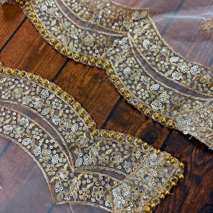 May include: White mesh fabric with gold embroidery and sequins. The fabric has a scalloped edge with gold beads.