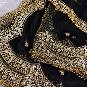 May include: Black sheer fabric with gold embroidery and beading. The fabric has a scalloped edge.