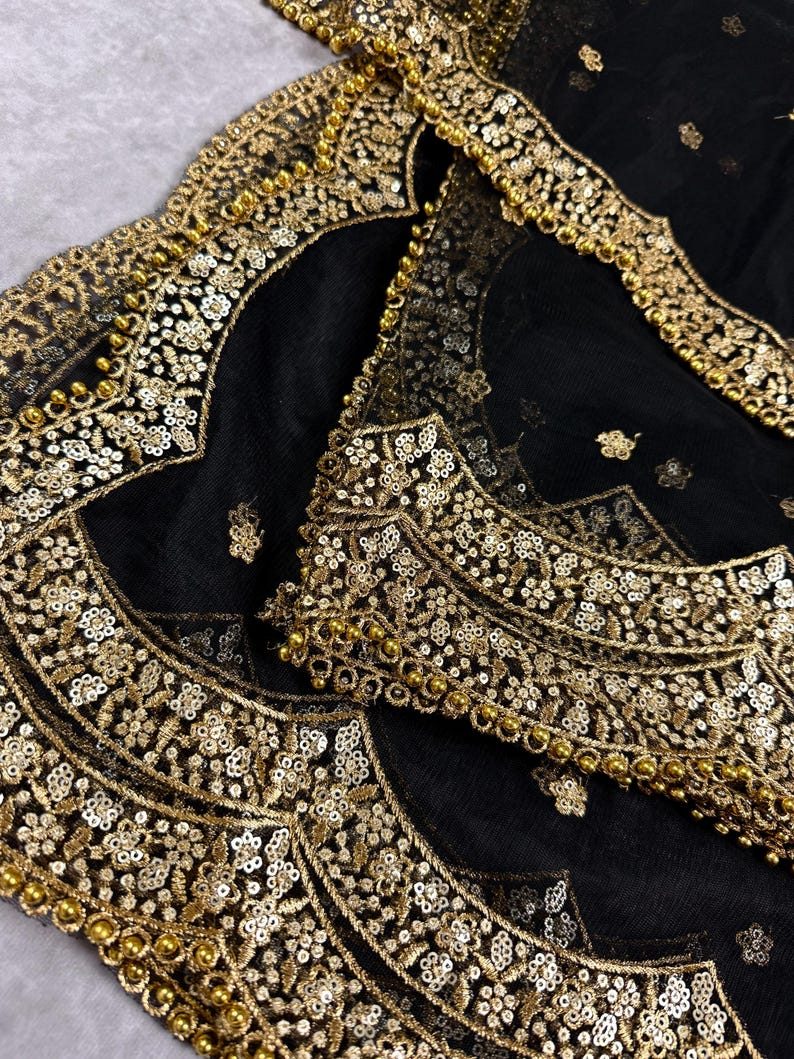 May include: Black sheer fabric with gold embroidery and beading. The fabric has a scalloped edge.