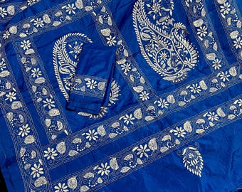 May include: A blue silk fabric with white embroidery featuring paisley and floral patterns. The fabric is folded in half and has a decorative border.