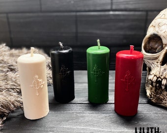 May include: Four pillar candles in white, black, green, and red with a black and white symbol on each. The candles are on a dark wood surface.