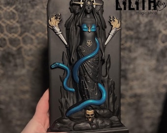 May include: Black and gold statue of the goddess Hecate, with a blue snake wrapped around her. The statue is on a black base with the text "Hecate by Lilith Magic with the blessing of Anastasia" on the front.