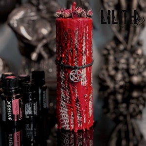 Pode incluir: Uma vela vermelha com um amuleto de pentagrama e botões de rosa secos no topo. A vela está pingando cera e tem um design texturizado, semelhante à pele de cobra. A vela está sobre uma superfície preta com várias garrafas pequenas de óleos essenciais no fundo.