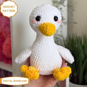 Peut inclure: Un canard blanc au crochet fait &agrave; la main, avec un bec et des pieds jaunes et des yeux noirs. Le canard a des joues roses et est &eacute;tiquet&eacute; "CROCHET PATTERN" et "DIGITAL DOWNLOAD". C'est un jouet en peluche doux.
