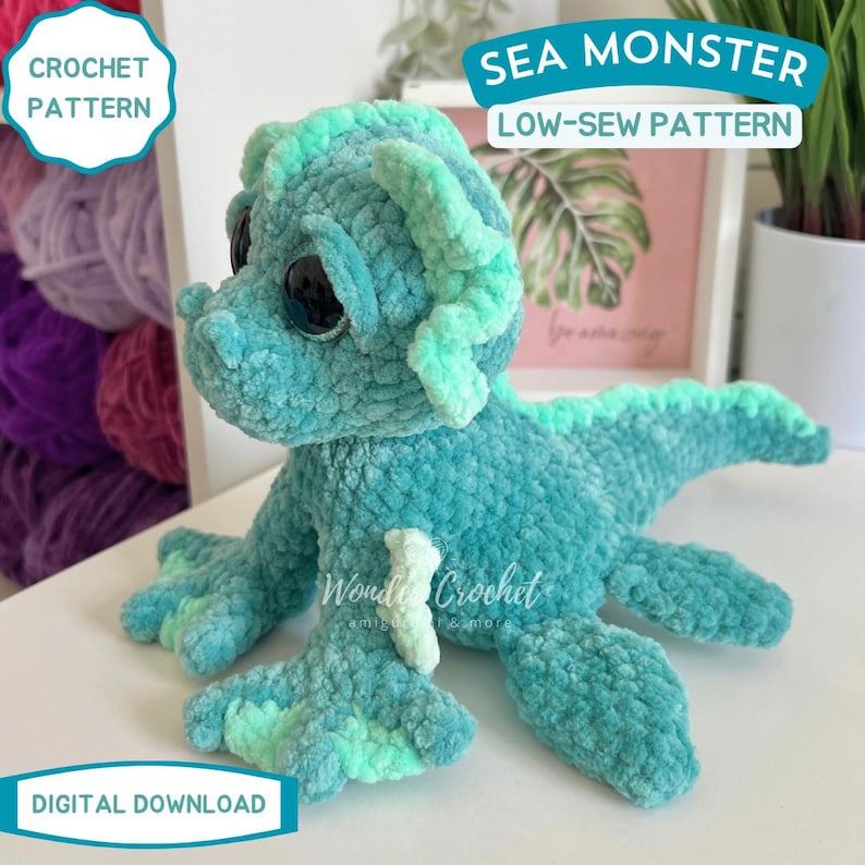 Peut inclure: Un jouet de monstre marin crochet&eacute; turquoise avec de grands yeux noirs et des accents vert clair. La cr&eacute;ature en peluche a un motif &agrave; faible couture et est &eacute;tiquet&eacute;e "Sea Monster" et "Crochet Pattern". Les mots "Digital Download" sont &eacute;galement visibles.