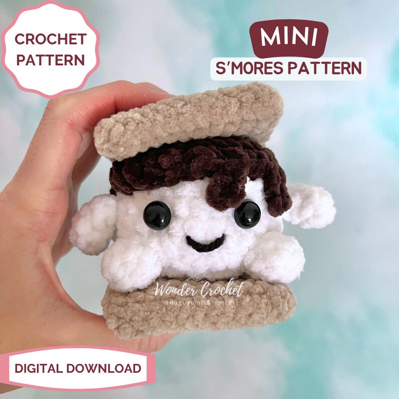 K&ouml;nnte beinhalten: Ein geh&auml;keltes Amigurumi-S'more mit einer braunen Schokoladen-Schicht, einem wei&szlig;en Marshmallow und zwei Graham-Cracker-Schichten. Das S'more hat ein l&auml;chelndes Gesicht mit schwarzen Augen. Der Text "MINI S'MORES PATTERN" und "Wonder Crochet" ist auf dem Bild zu sehen.
