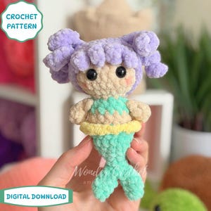 May include: Crocheted mermaid doll with purple hair, black eyes, and a turquoise tail. The doll has a light tan face and body, with a turquoise and yellow top. The image includes text that says "CROCHET PATTERN" and "DIGITAL DOWNLOAD".