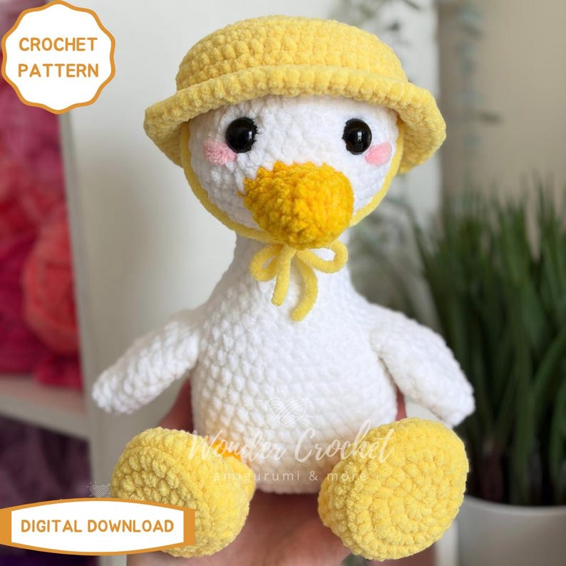 Peut inclure: Un amigurumi de canard crochet&eacute;, portant un chapeau et un n&oelig;ud jaune. Le canard a un corps blanc, des pieds et un bec jaunes, et des yeux noirs. Le texte "CROCHET PATTERN" et "DIGITAL DOWNLOAD" est visible.