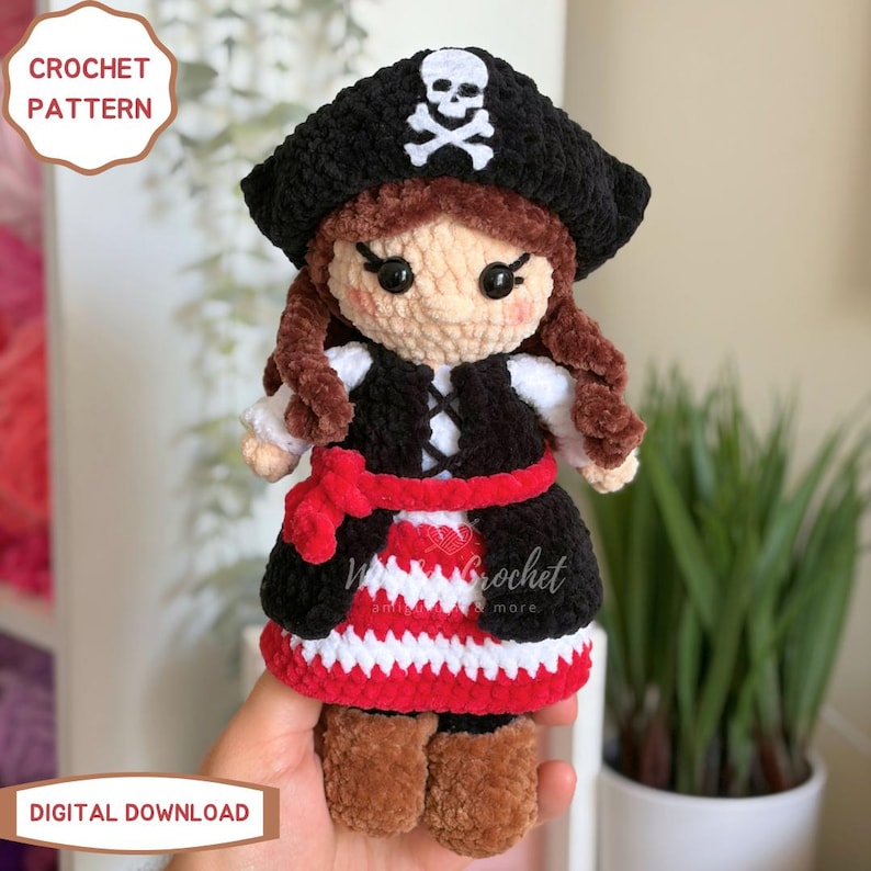 K&ouml;nnte beinhalten: Eine H&auml;kelpuppe mit einem schwarzen Piratenhut mit wei&szlig;em Totenkopf, braunen Haaren, einer schwarzen Weste, einer roten Sch&auml;rpe und einem rot-wei&szlig; gestreiften Rock. Der Text CROCHET PATTERN und DIGITAL DOWNLOAD ist auf dem Bild zu sehen.