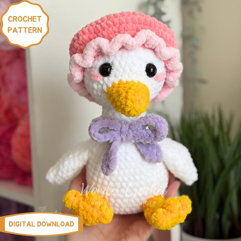 Peut inclure: Un adorable canard blanc en crochet, orn&eacute; d'un bonnet rose et d'un n&oelig;ud papillon violet. Le canard a un bec et des pattes jaunes. Le texte "CROCHET PATTERN" et "DIGITAL DOWNLOAD" est visible.
